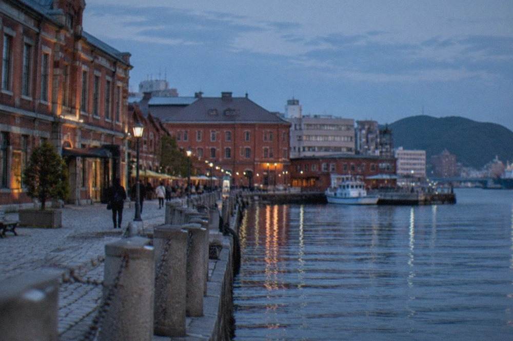 Historic red brick harbour buildings along a waterfront promenade on a clear afternoon