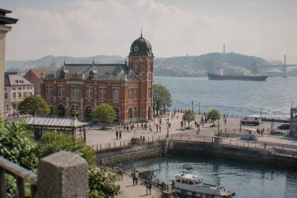 A restored brick railway building with a domed tower beside a waterfront plaza