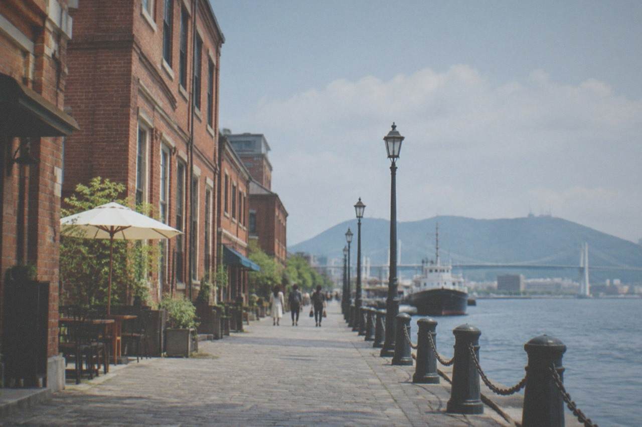 Historic red brick harbour buildings along a waterfront promenade on a clear afternoon
