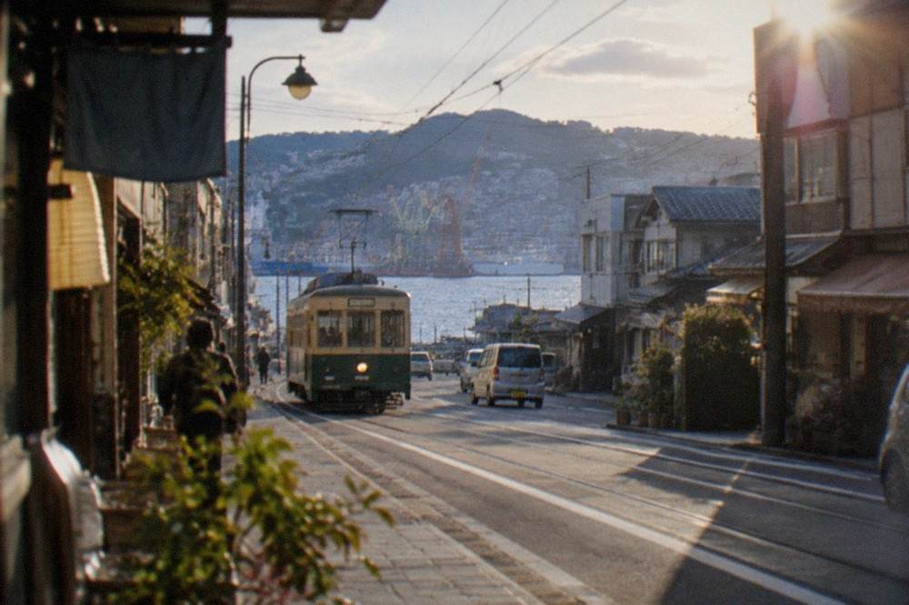 Tram travelling along a narrow street lined with shops in Nagasaki