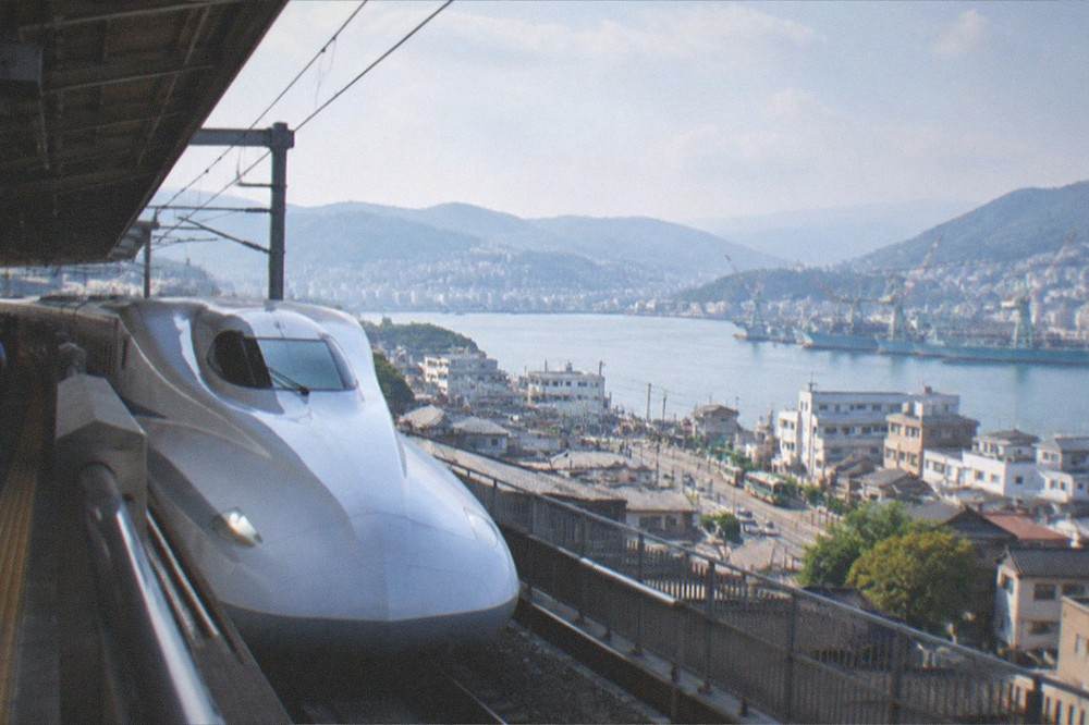 Long-distance bullet train stopped at a station platform under a covered roof