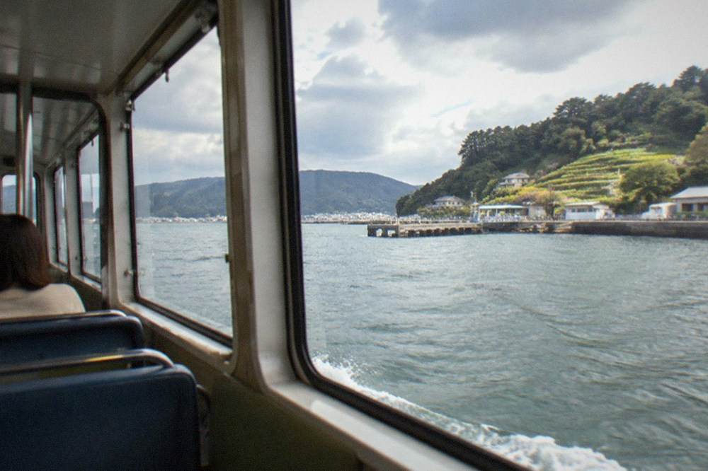 Small ferry cabin interior with bench seating and a view of the bay through the windows