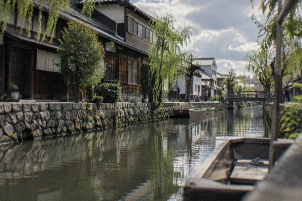 Old wooden townhouses along a quiet canal in Yanagawa with reflections in the still water