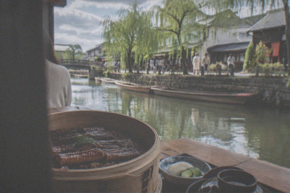 Steamed eel over rice served in a round bamboo seiro basket on a wooden table