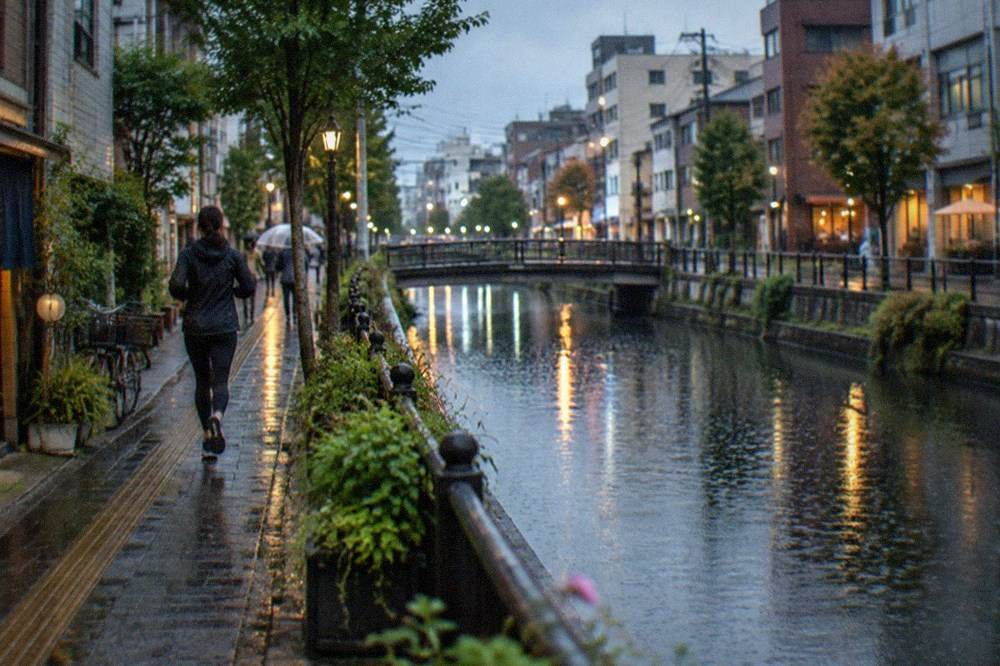 Raindrops falling on a canal running between city buildings at dusk