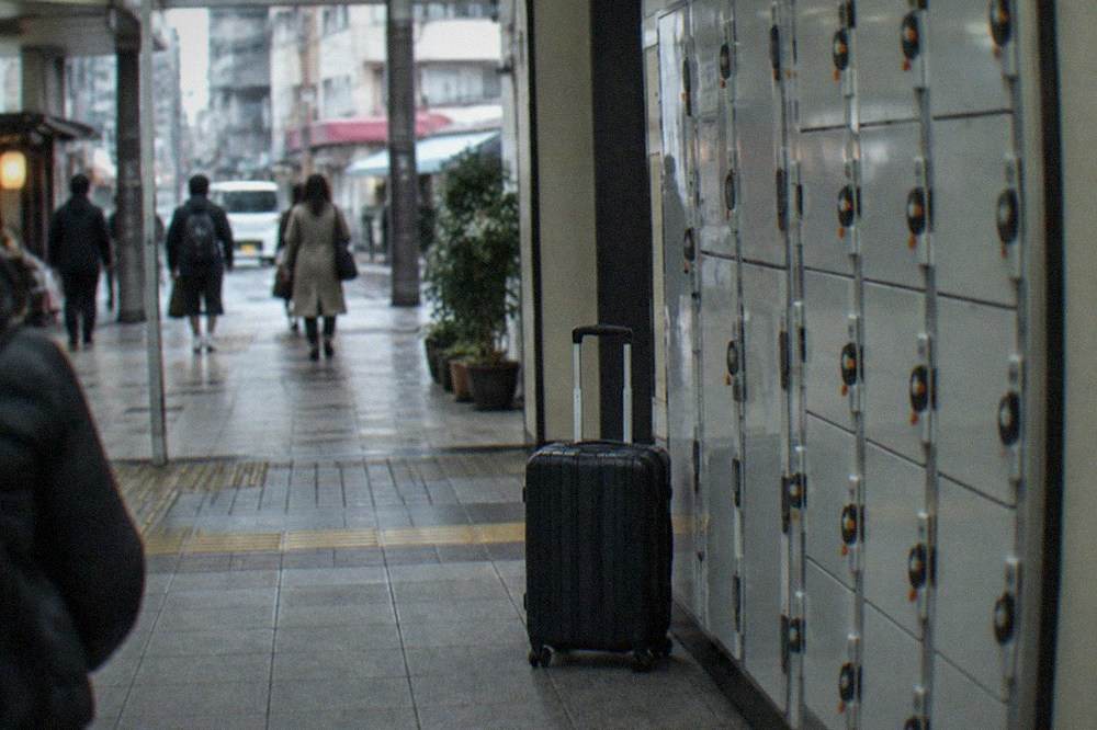 Rows of coin lockers along a station corridor with a suitcase in front of them