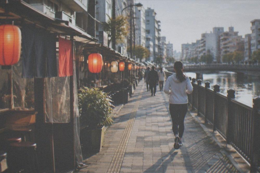 Food stalls with lanterns lit along a riverside walkway in the evening