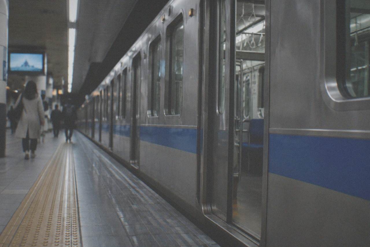 A subway platform at Fukuoka Airport station with a train waiting at the doors