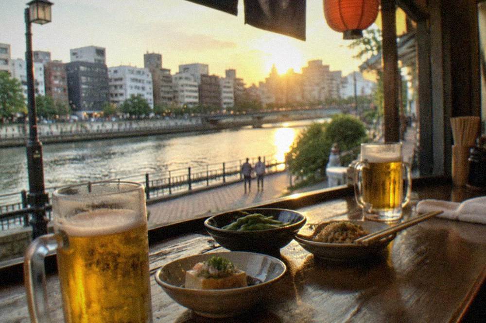 Wooden counter of a small izakaya with glasses of beer and small dishes of food