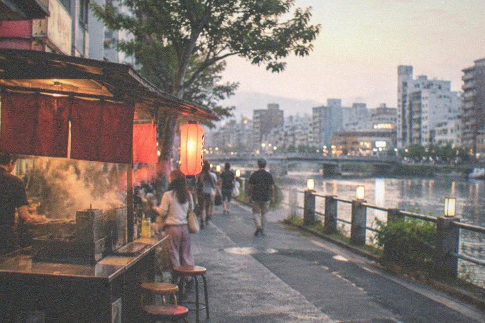 Food stall with steam rising from a cooking counter beside a city street at dusk