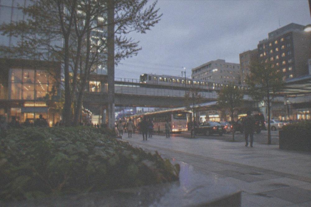 City hotel district at dusk with lit windows and a train line overhead