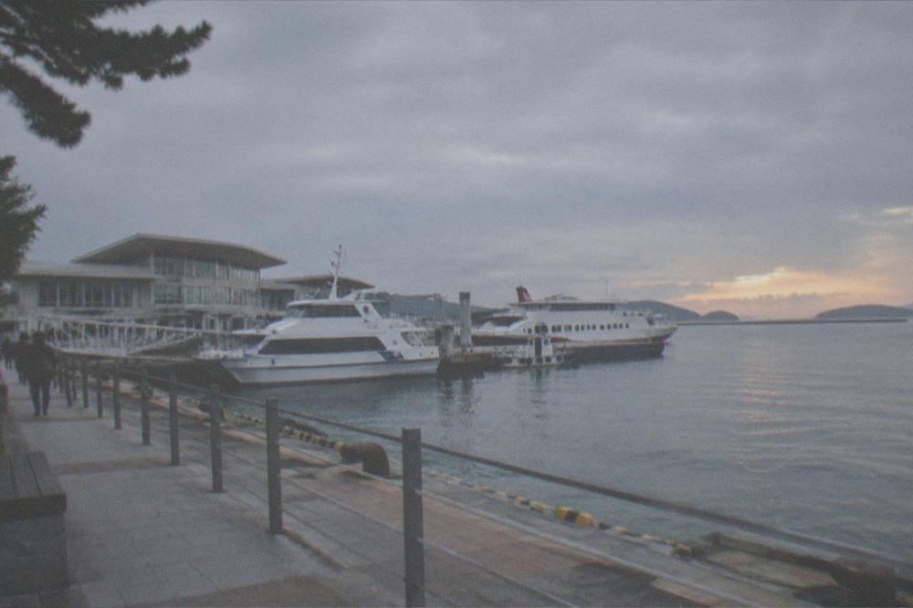 A calm bay at sunset with islands visible on the horizon under a wide sky