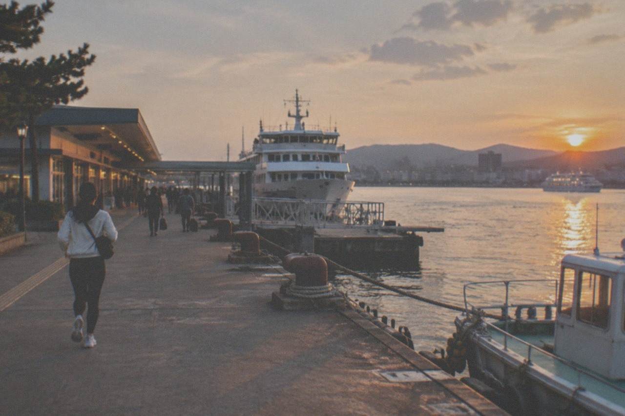 A cruise boat on calm evening water with city lights reflected across a wide bay