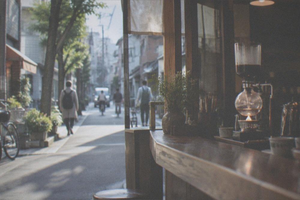 A siphon coffee maker brewing behind a wooden kissaten café counter