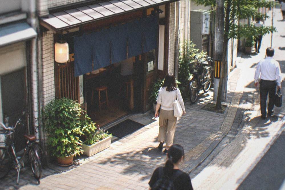 The entrance to a small neighbourhood udon shop with a noren curtain in morning light