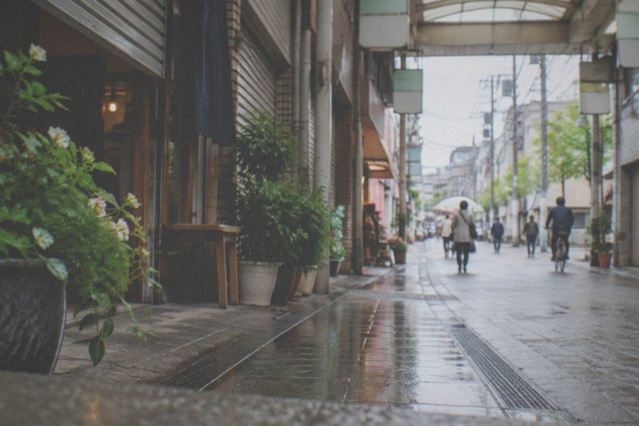 A quiet shopping arcade street in Hakata in early morning light with shutters half open