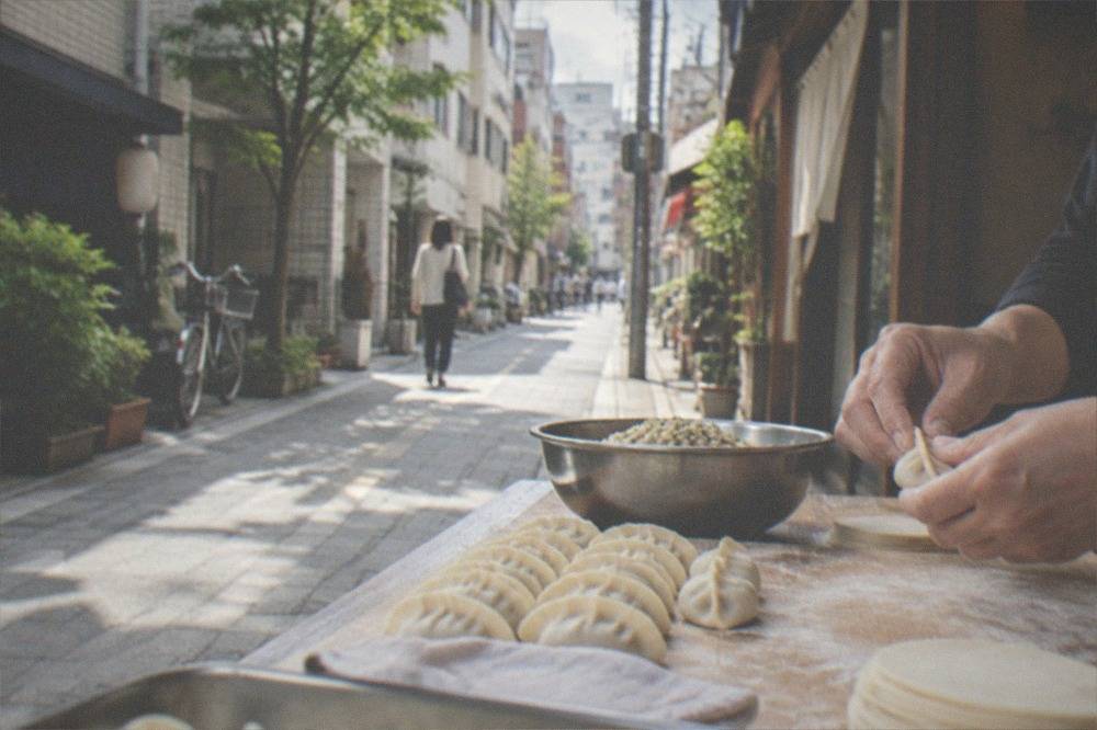 Hands folding small gyoza dumplings on a floured wooden board in a class kitchen