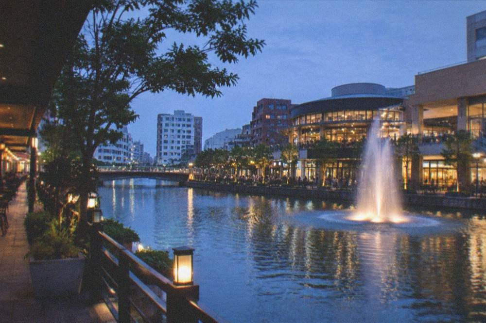A night view of a canal-side shopping complex in Fukuoka with illuminated walkways and a fountain