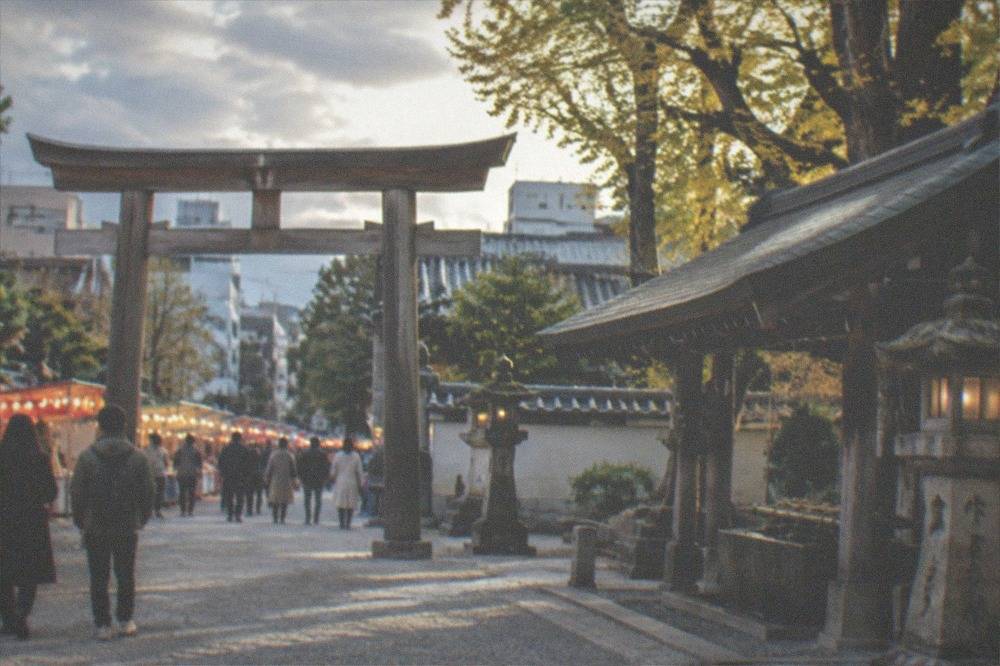 Lantern-lit shrine approach lined with food stalls and visitors in the evening