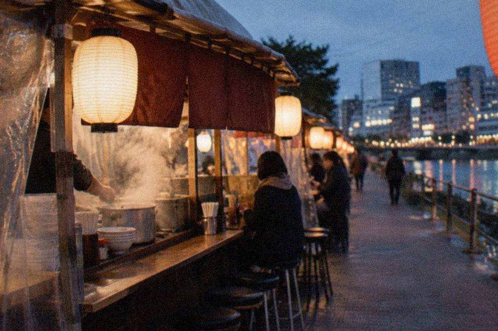 Steam rising from a ramen pot at a small street food stall counter