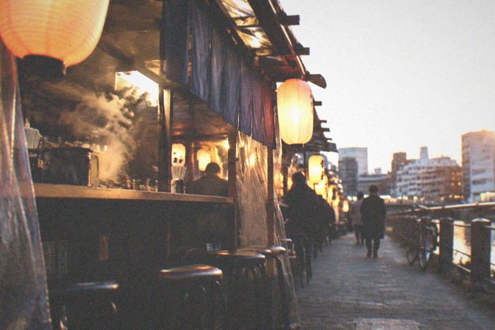 Covered shopping arcade with small food stall fronts and hanging signs