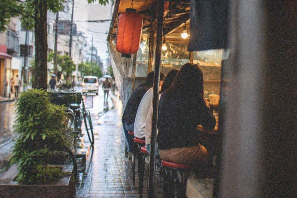 Group of diners seated at an outdoor food stall counter in the evening