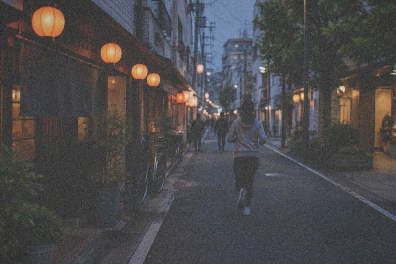 A quiet Fukuoka restaurant street at dusk with lanterns glowing above closed storefronts