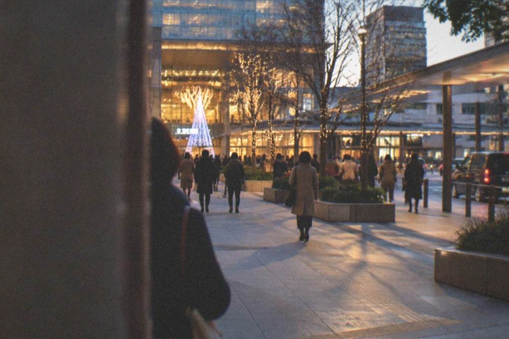 Hakata Station entrance at night in winter with illuminated decorations and commuters passing under warm lights