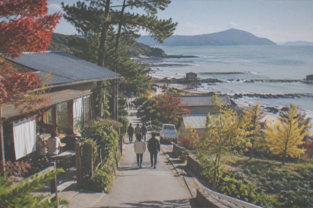 Oyster shacks and calm sea along the Itoshima coast on a clear day