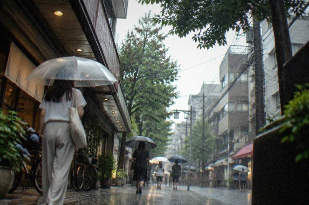Heavy rain sweeping across a Fukuoka shopping street with pedestrians under umbrellas