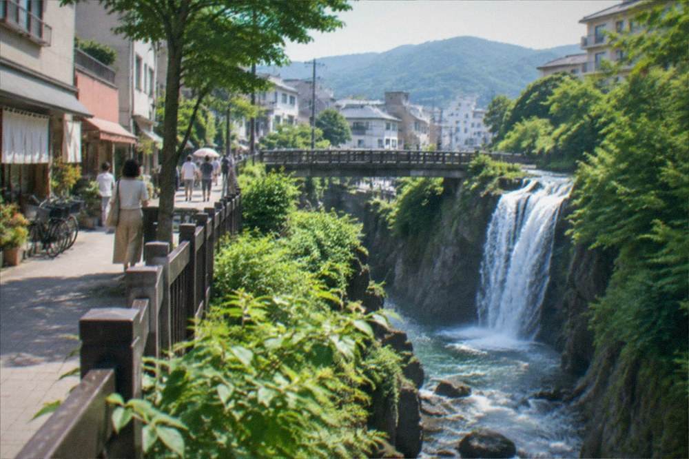 Cool green gorge with a waterfall dropping into a narrow river between cliff walls