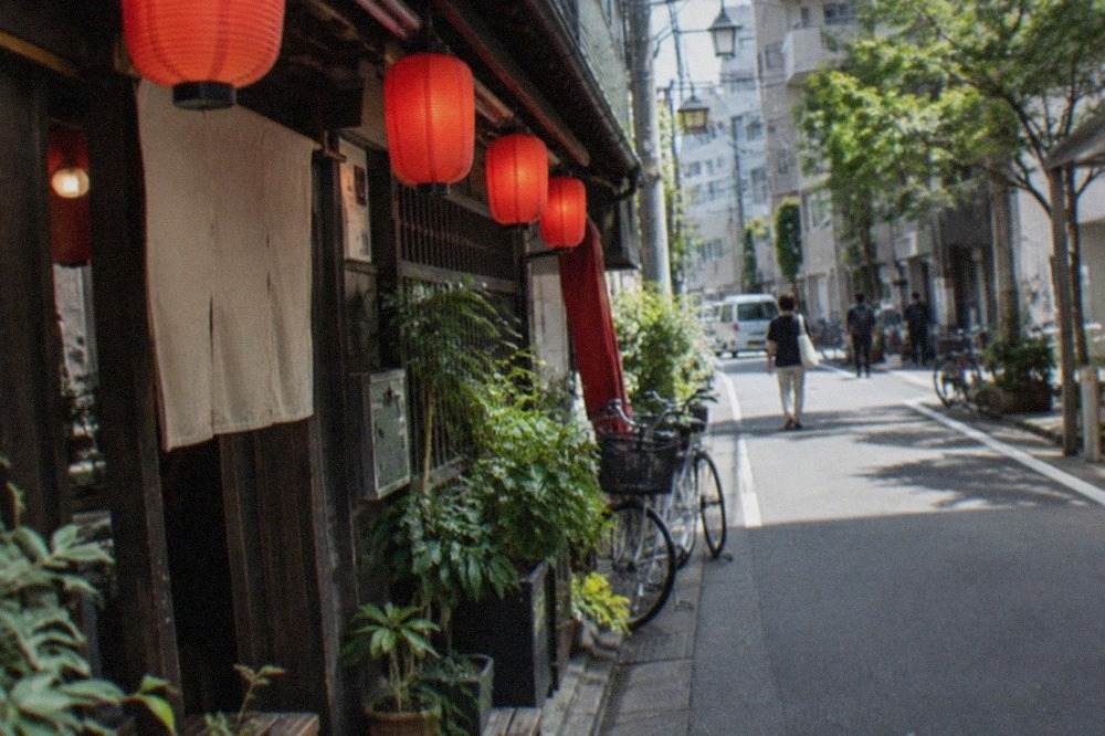 Red paper lanterns glowing above a narrow alley of small bars at night