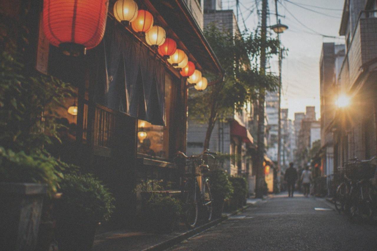 Warm lantern light over a narrow izakaya street at night in Fukuoka