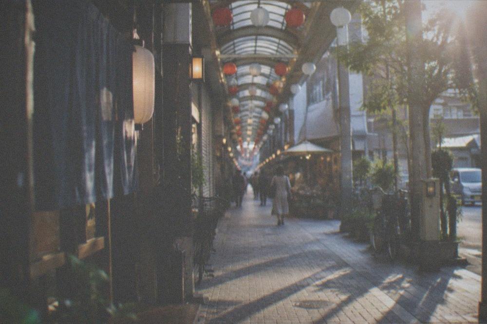 A narrow arcade street of small shops with lanterns strung across the ceiling