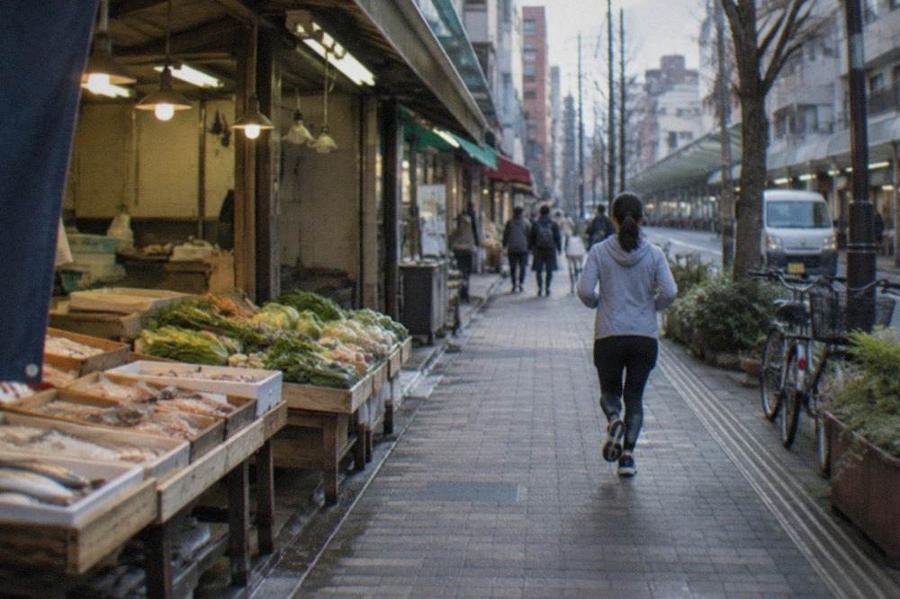 Covered market stalls with fresh vegetables and seafood displayed in wooden trays under warm lights