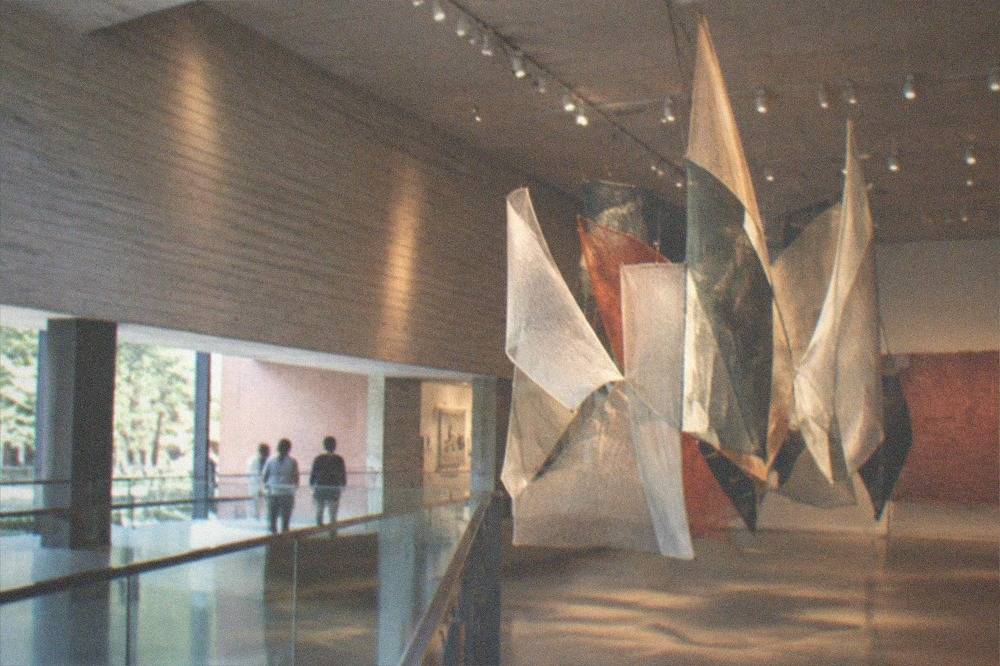 Contemporary art gallery mezzanine with large installations under spotlights