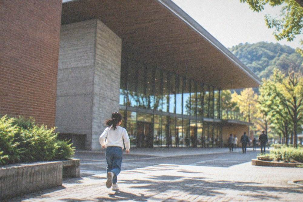 Large museum atrium with a sweeping roof and glass wall overlooking wooded hills