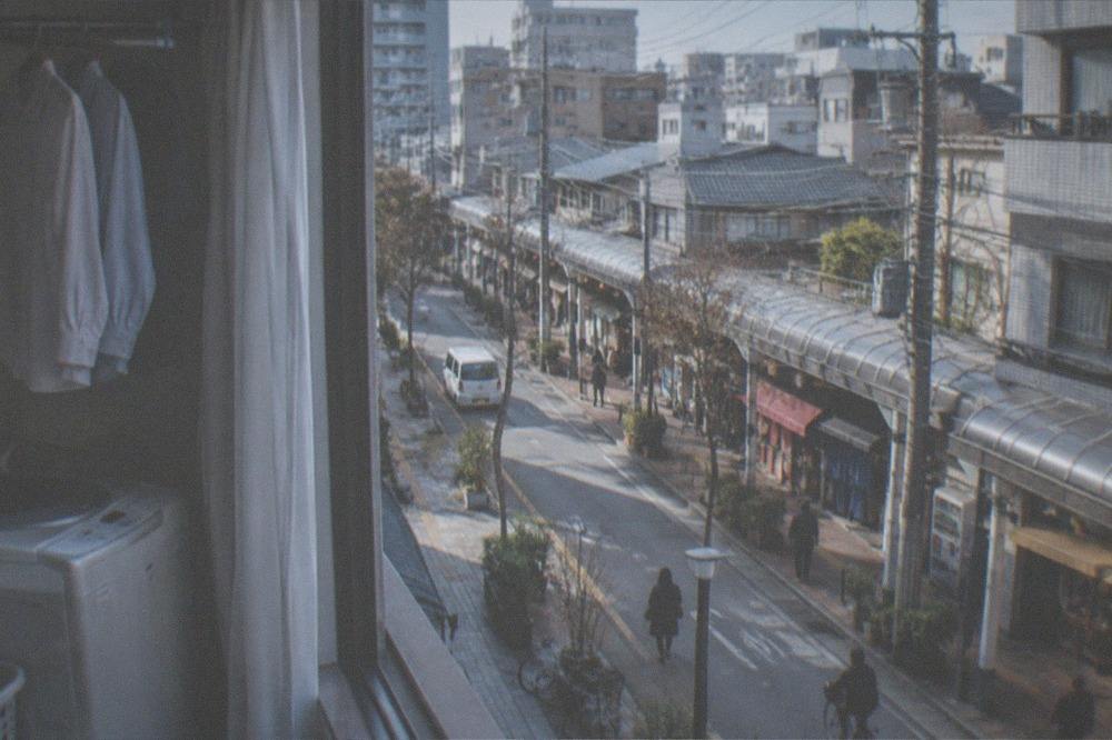 A hotel room with a small washing machine and quick dry shirts hanging to dry near a window
