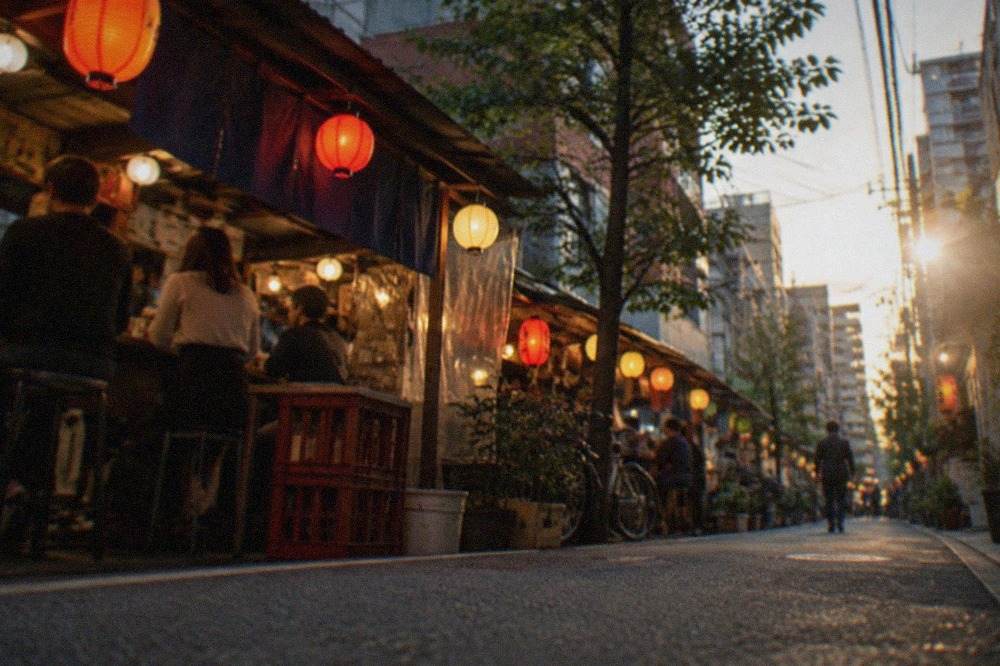 Evening view of a narrow street in Fukuoka with lanterns glowing above small food stalls