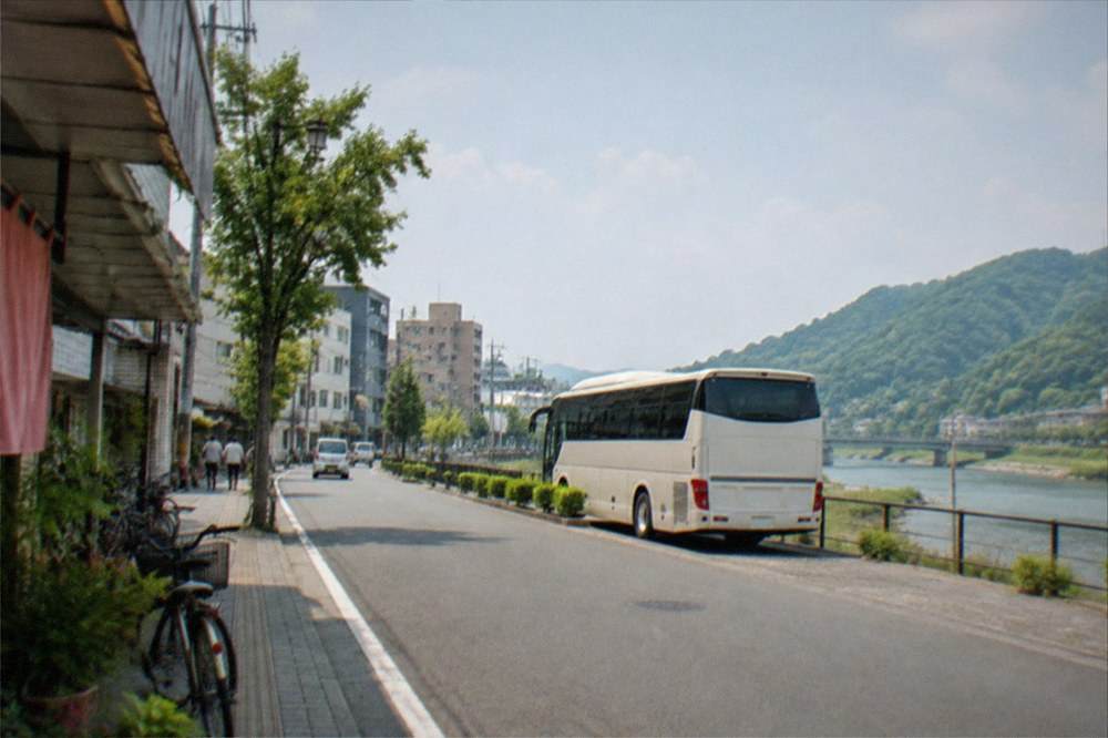 A tour bus parked beside a green rural valley with a river running through it