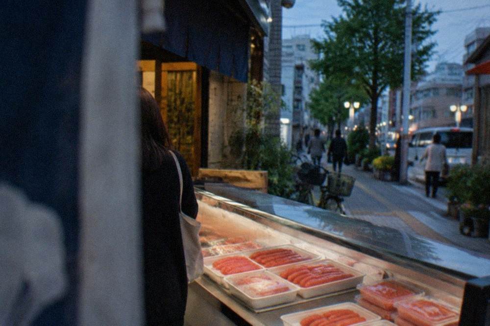 Red mentaiko roe in sealed trays displayed in a refrigerated souvenir counter