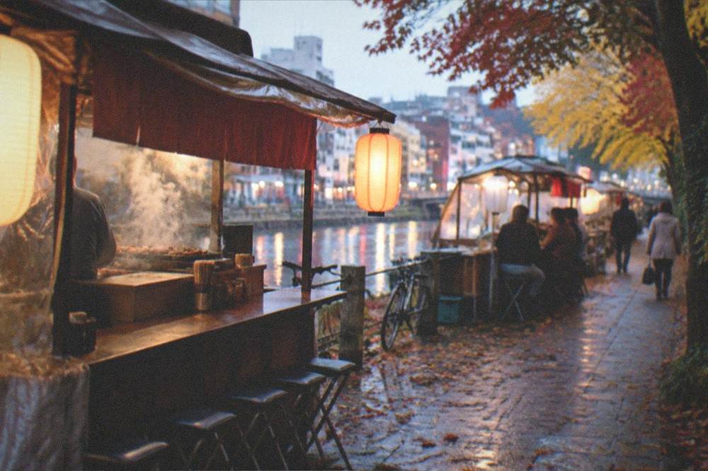 Steam rising from a food stall grill on a cool autumn evening with leaves on the pavement