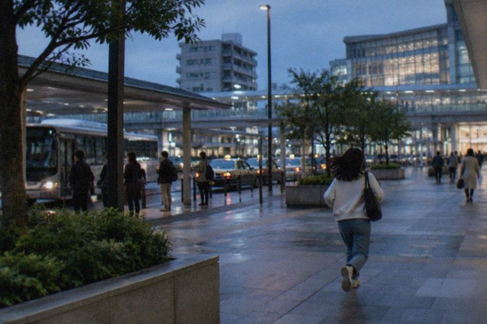 A clean modern subway platform in Fukuoka with a train arriving and passengers waiting