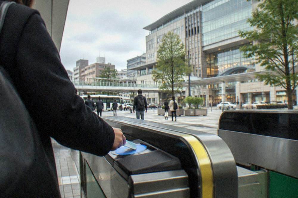 A passenger tapping a transit card at a subway station gate in Fukuoka