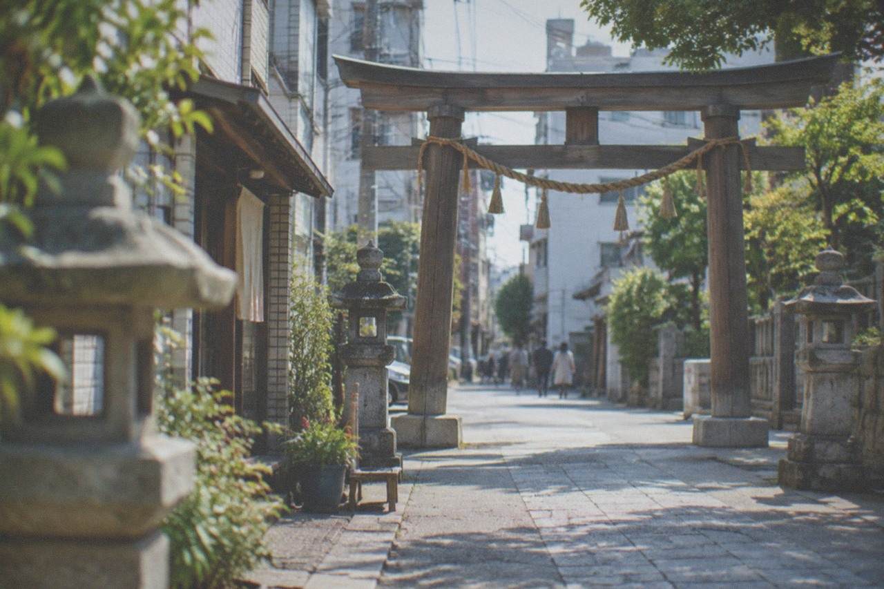 A wooden shrine gate and stone lanterns along a quiet path in Hakata, Fukuoka