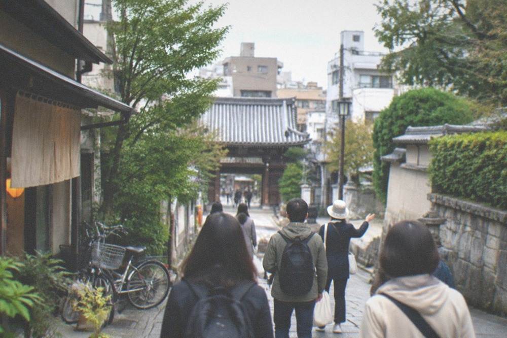 A small group following a guide along a historic temple street in Fukuoka
