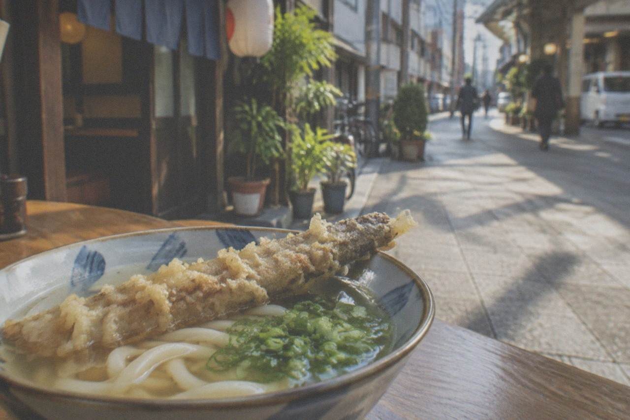 A bowl of Hakata udon with a crisp burdock tempura resting on soft noodles in clear broth