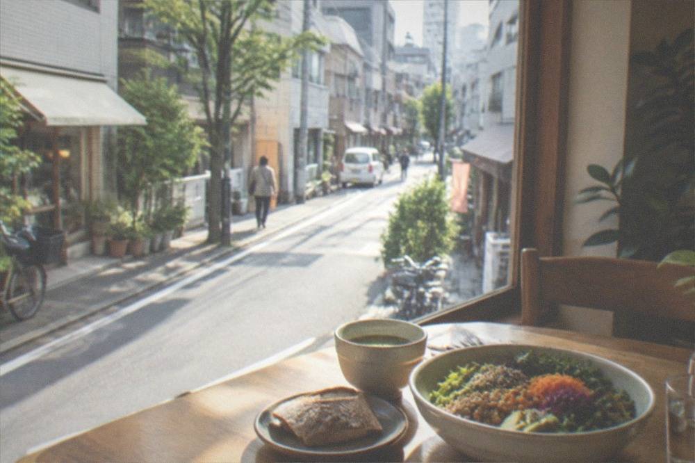 A quiet cafe interior with wooden tables and plant-based dishes set out near a window
