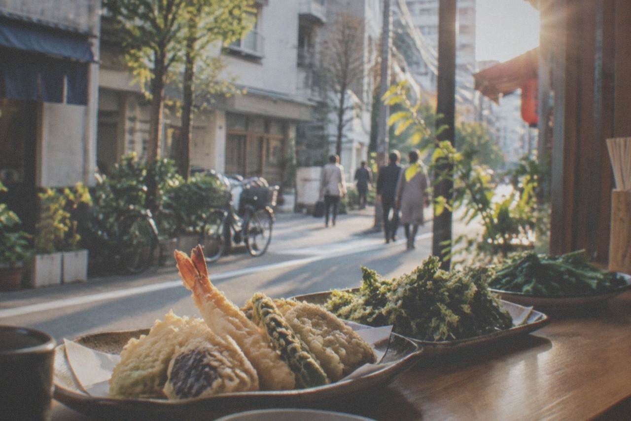 Fresh vegetable tempura and greens arranged on a wooden counter in a small Fukuoka restaurant