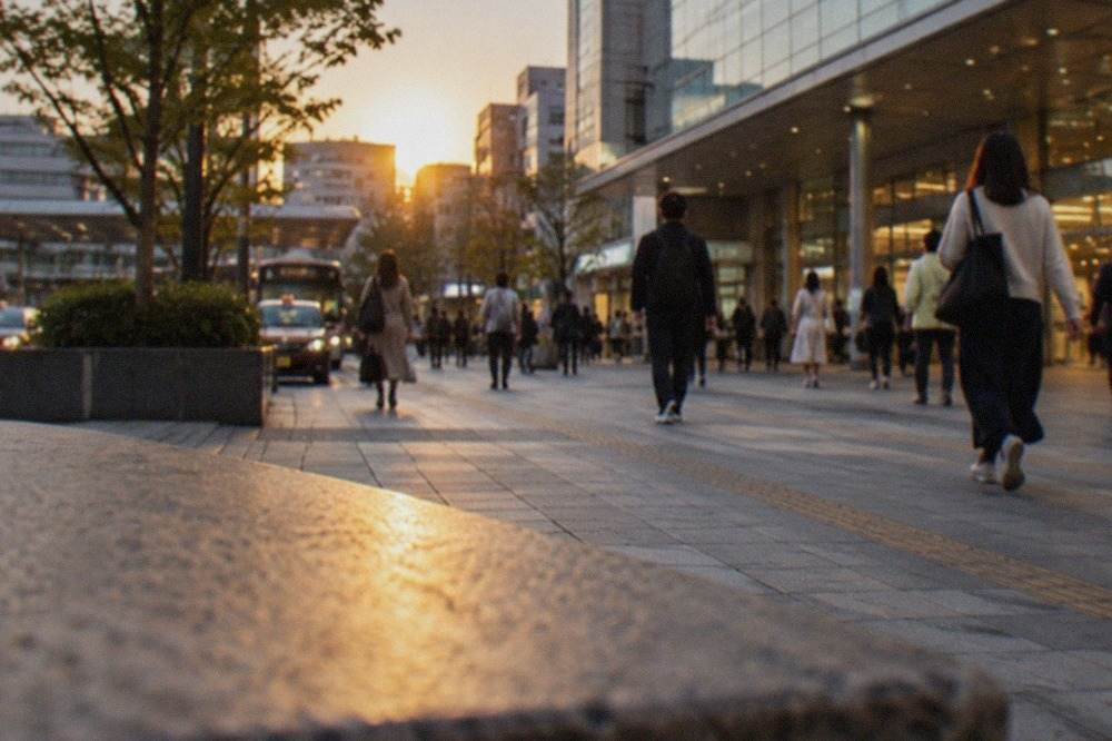 Hakata Station exterior with travellers walking past the glass entrance at dusk